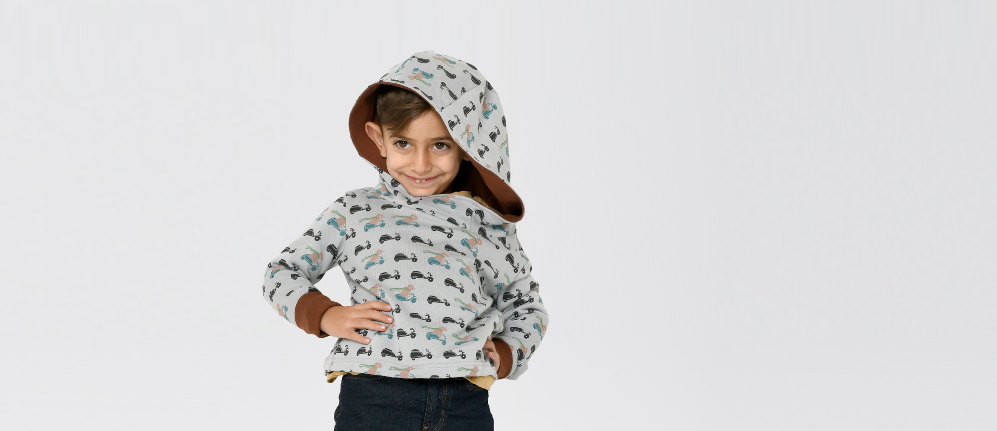 Kleiner Junge, grinsend, mit grauem Hoodie mit Scooterbären Print